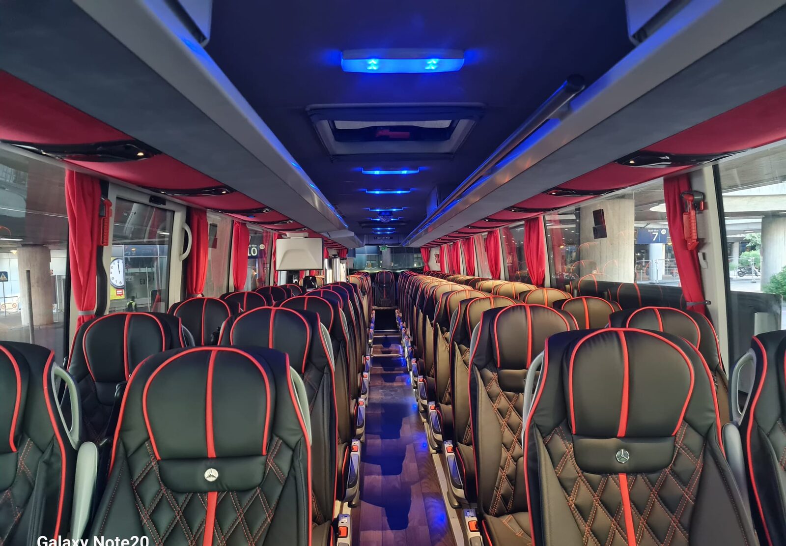 Innenraum des Reisebusses: Ledersitze mit roten Akzenten und blauer Ambientebeleuchtung